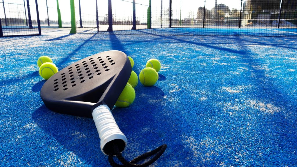 Padel racket and tennis balls on padel court.